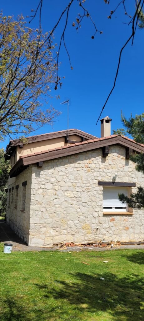 Arreglo de aleros - Riaza 2 Top Tejados Toledo Casa de piedra con techo inclinado en proceso de arreglo de aleros, mejorando la durabilidad y la protección contra el clima
